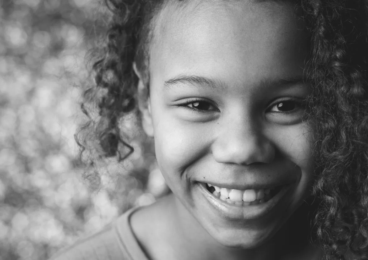 Schwarzweißes Kinderporträt, lachend, mit lockigem Haar vor weichem Bokeh
